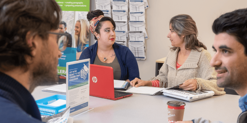 International students sit around a table, talking, in an office at Georgian College.