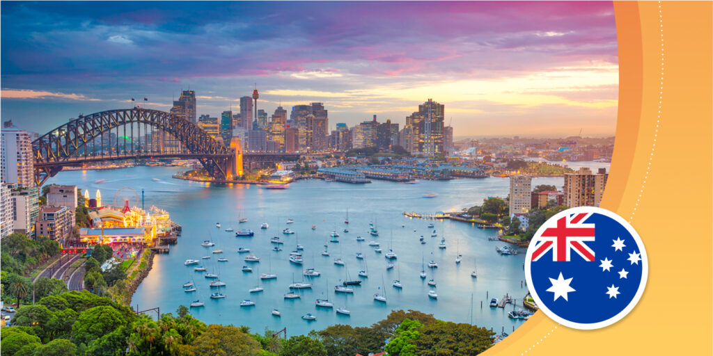 A seaside view of an Australian city; a curved bridge over a blue bay and a downtown skyline with tall towers.