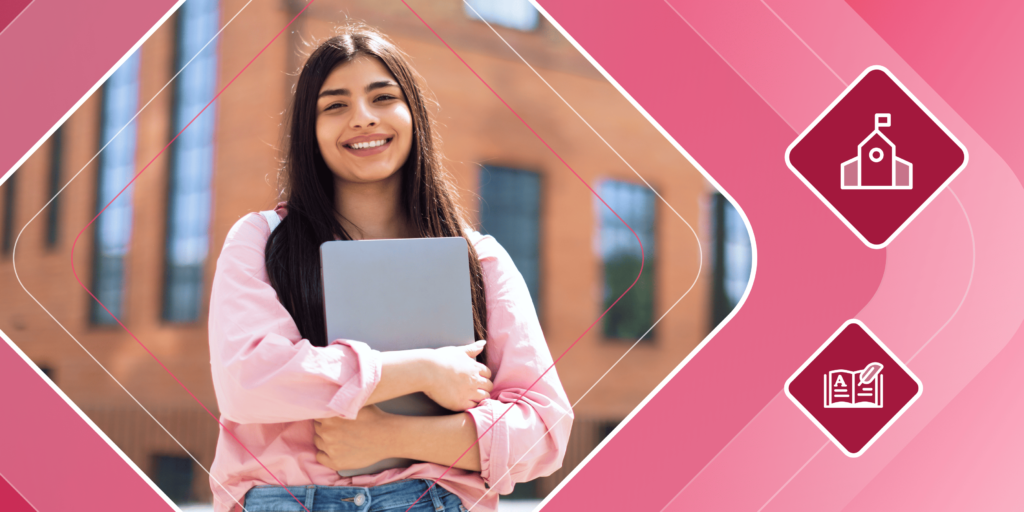 Smiling international student stands in front of a building holding a laptop