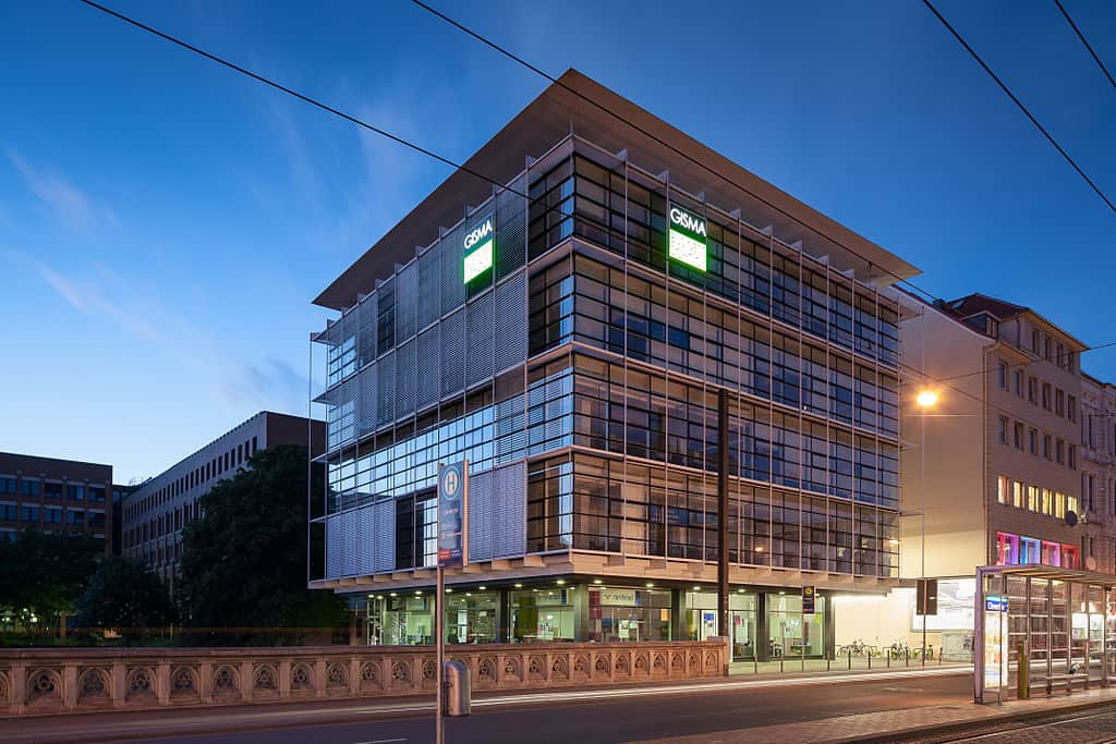 A tall, modern university campus building at night. (Gisma University - Hanover campus)