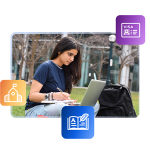A female student sits on the grass in front of a university, writing in a notebook with her laptop open in front of her and a backpack beside her