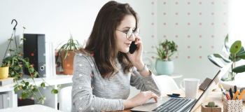 A photo of a woman sitting at her desk working on her laptop.