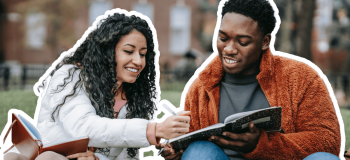 Two black international students on an American campus, reading about Black History Month.