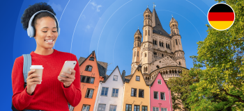 A smiling young woman looks down at her phone while holding a white to-go coffee mug. She is framed by a photographic background with colourful multistorey houses, a warm-hued stone castle, and a German flag logo.