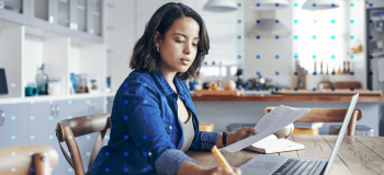 A photo of a woman sitting at her desk working on her laptop.